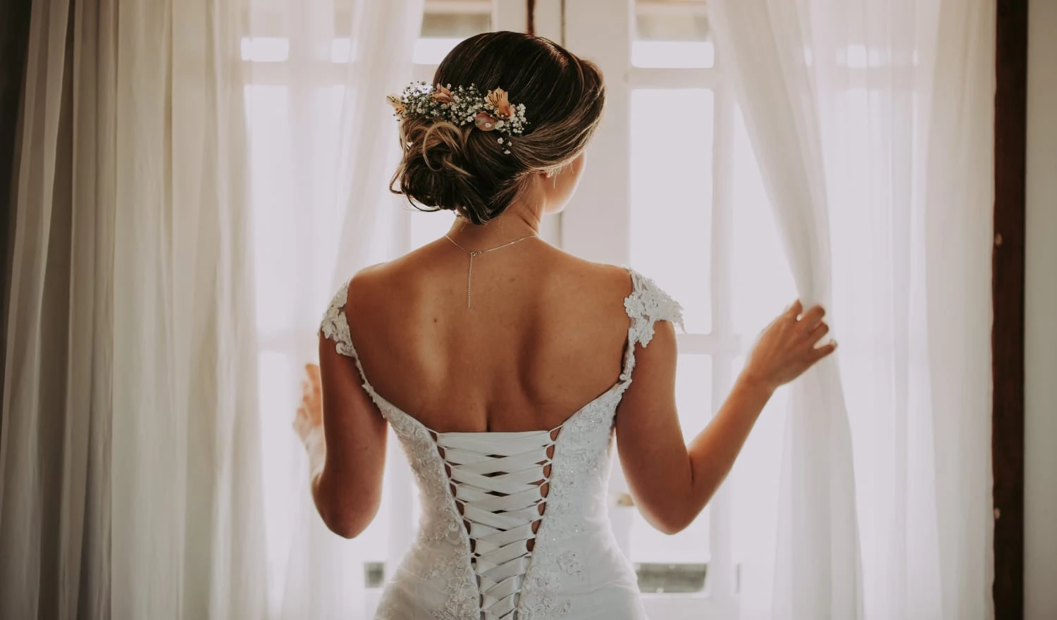 A bride looking looking out through curtains