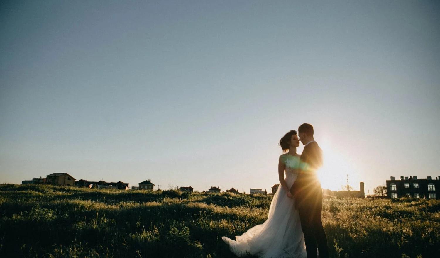 Newlyweds standing on a grassy hill