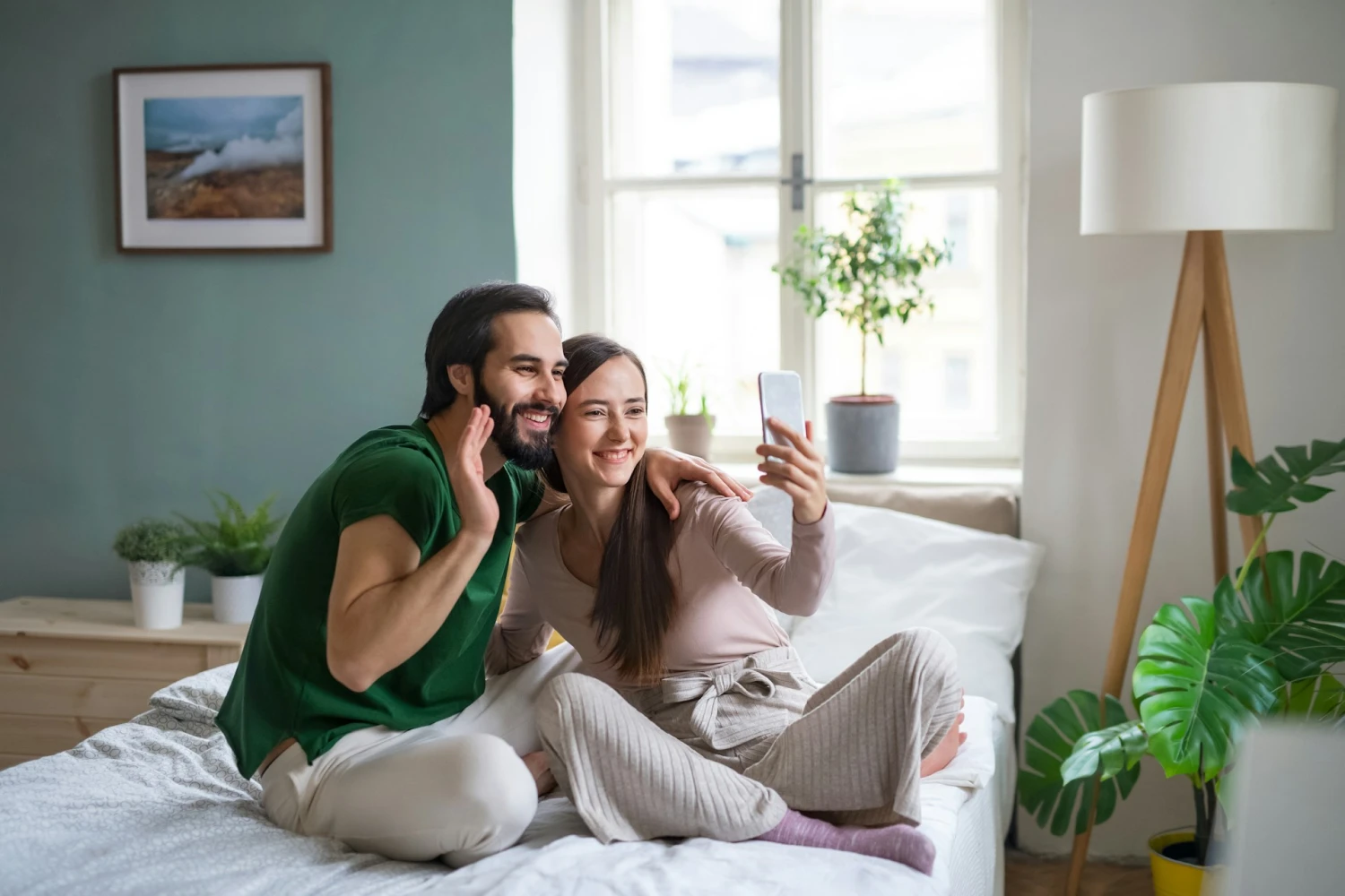 An engaged couple taking a selfie-style video on their phone for their wedding website