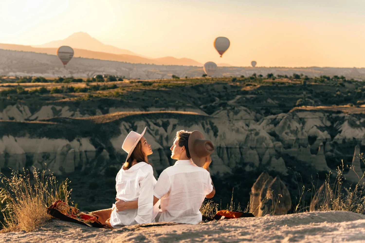 Newlyweds watching hot air balloons from a cliff