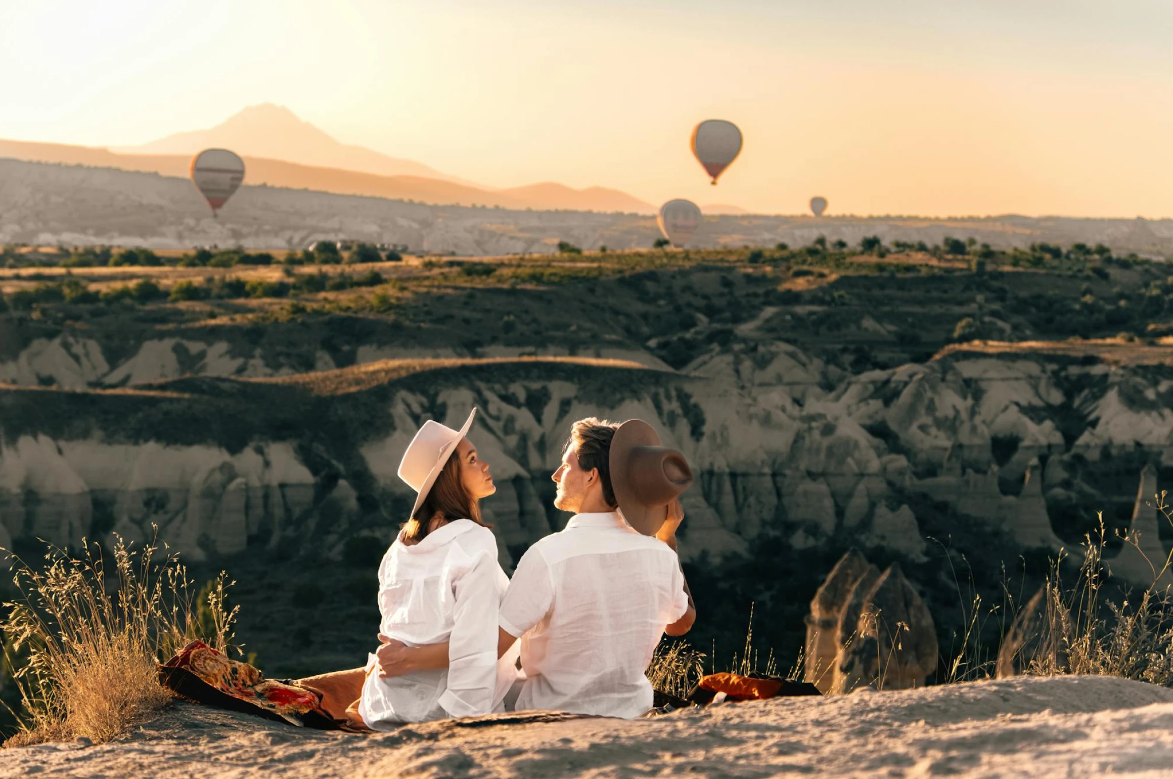 Newlyweds watching hot air balloons from a cliff